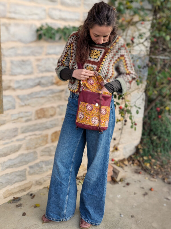 Femme ouvrant le sac Évolution Nomade porté en bandoulière, vue en extérieur, patron sac transformable.