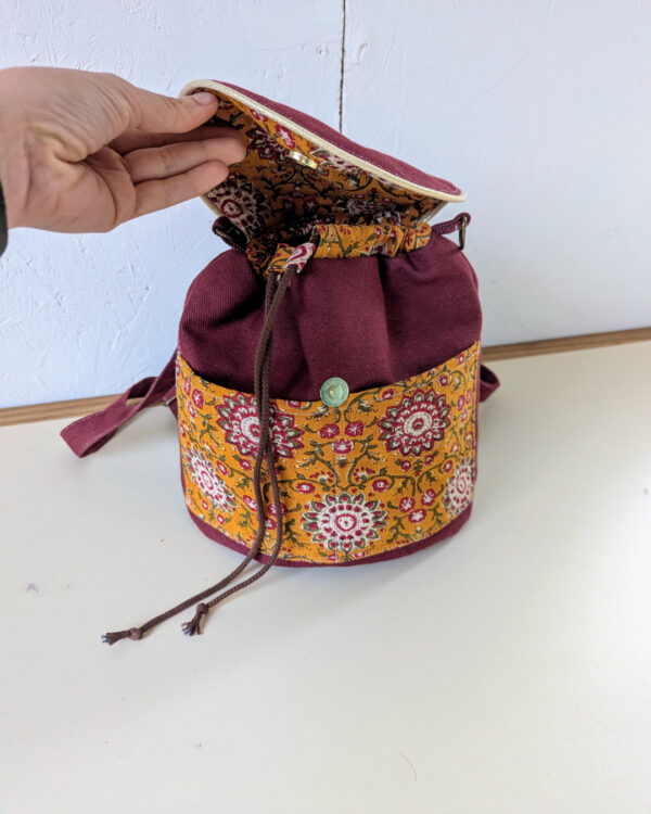 Ouverture du sac Évolution Nomade avec rabat relevé, doublure imprimée et cordons visibles, patron sac bandoulière transformable.