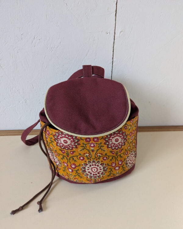 Sac Évolution Nomade fermé, tissu camel imprimé et haut bordeaux, patron sac bandoulière et sac à dos transformable.