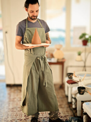 tablier de poterie vert olive en lin coton sur mannequin dans un atelier