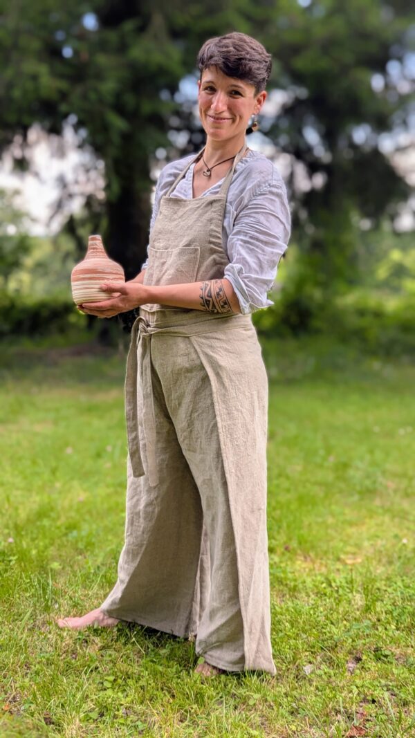 tablier en lin brut porté par une ceramiste qui présente un vase en terre cuite