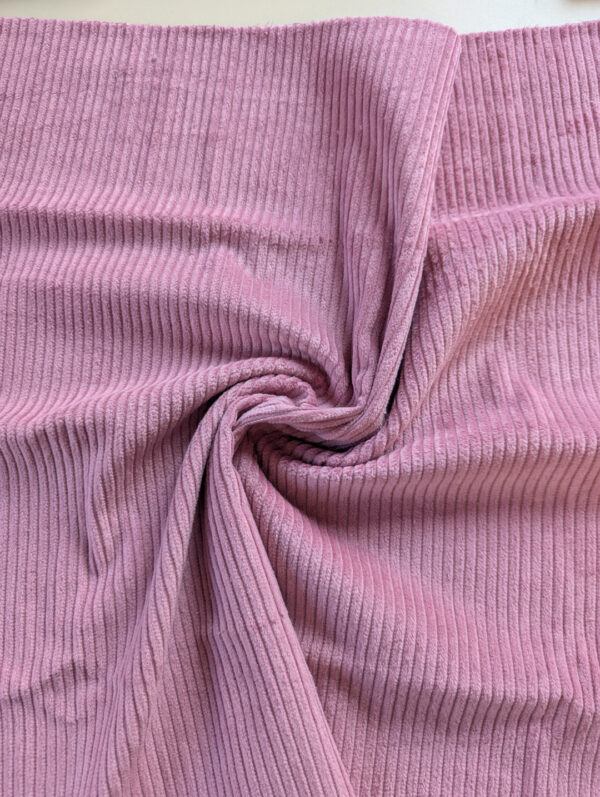 Détail du tissu velours côtelé vieux rose, texture douce et lumineuse.