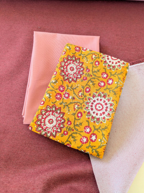 Lot de coupons tissu couture : denim rouge recyclé, coton bio vieux rose et voile de coton fleurs ocre.
