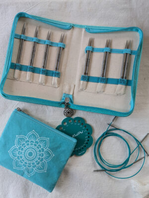Étui ouvert du kit d’aiguilles circulaires interchangeables KnitPro Mindful Believe, montrant les pointes métalliques de 3 à 6 mm rangées par taille, accompagnées de câbles et accessoires turquoise.