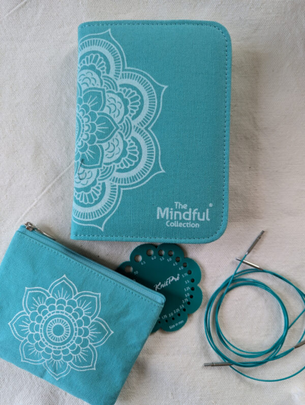 Vue d’ensemble du kit d’aiguilles circulaires interchangeables KnitPro Mindful Believe avec étui turquoise, petite trousse, jauge à aiguilles et câbles 360°.