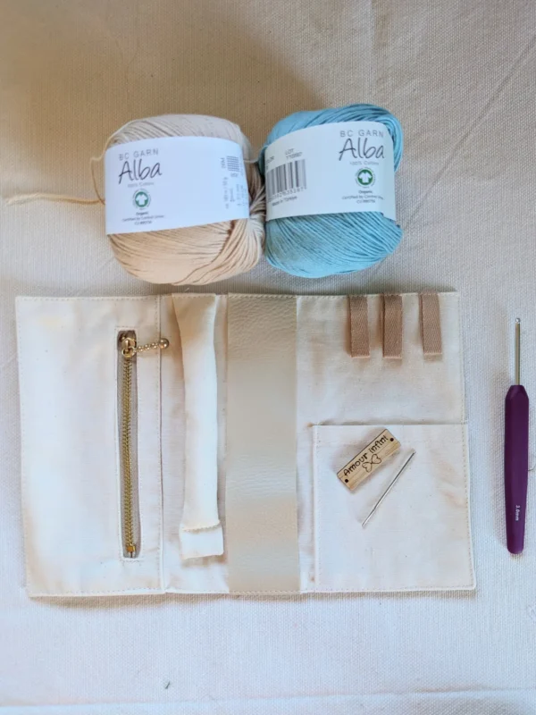Contenu de la box crochet pour réaliser une trousse à bijoux nomade avec coton bio, doublure cousue, étiquette en bois, crochet et aiguille à laine.