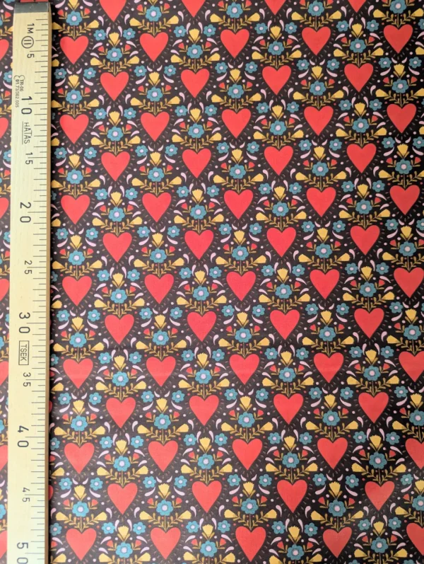 Tissu coton Danyl à grands cœurs orange-rouge, petites fleurs bleu turquoise et feuillages moutarde sur fond chocolat, imprimé rétro années 70.