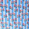 Tissu coton Tulip à tulipes rouges et roses sur rayures bleu ciel et écru. Un imprimé fleuri et coloré pour vêtements et accessoires. Laize 150 cm.