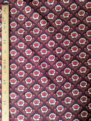 Velours milleraies Hoko à fleurs stylisées écrues et orange, feuillages bordeaux sur fond foncé, motif floral rétro.