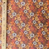 Velours milleraies Azylis à grandes fleurs orange, jaune moutarde, rouge brique et écru sur fond marron, motif rétro années 70.