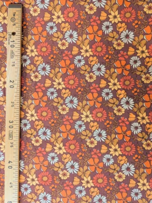Velours milleraies Azylis à grandes fleurs orange, jaune moutarde, rouge brique et écru sur fond marron, motif rétro années 70.